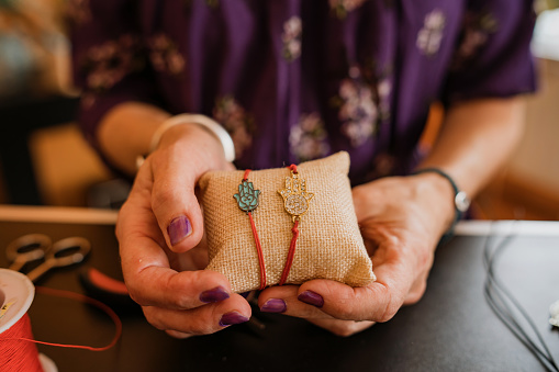 Close up shot of unrecognizable female hands holding hand made bracelets, hamza symbol.