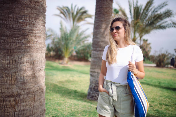 istock During a sunny day a woman walks through a park surrounded by palm trees. 1393041570