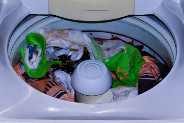 istock washing machine with the lid open, filled with clothes waiting to be washed inside. 1393050244