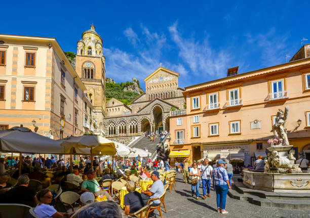 os turistas gostam de passear e jantar em um café de calçada na piazza duomo com a fonte fontana sant'andrea e degraus amalfitanas, e catedral em vista em amalfi, itália. - campania - fotografias e filmes do acervo