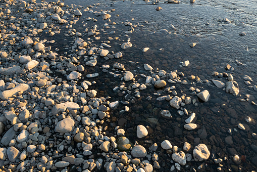 Cobblestones of the lakeshore with sunlight
