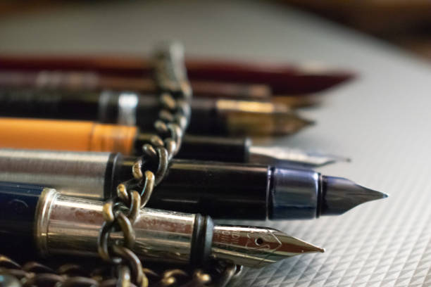 peu de stylos enveloppés dans une chaîne de fer reposent sur la table. - poetic photos et images de collection