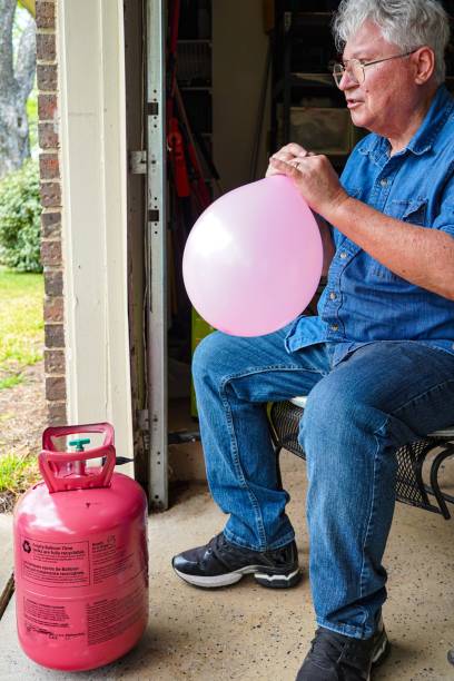 istock Senior Man Inflates Helium Balloon 1393058080