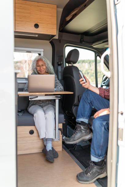istock Senior woman working on computer while traveling in camper van 1393058320