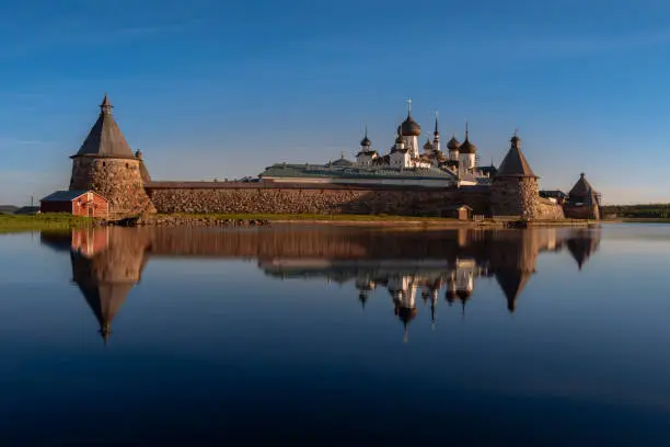 Spaso-Preobrazhensky Solovetsky Monastery with a mirror reflection in the Holy Lake on a sunny cloudless morning, Solovetsky Island, Arkhangelsk region, Russia
