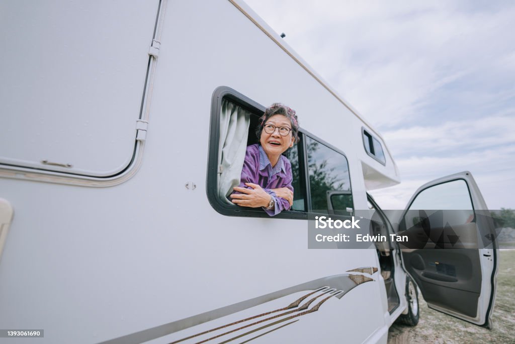 happy Asian chinese senior woman looking away from motor home window Senior Adult Stock Photo