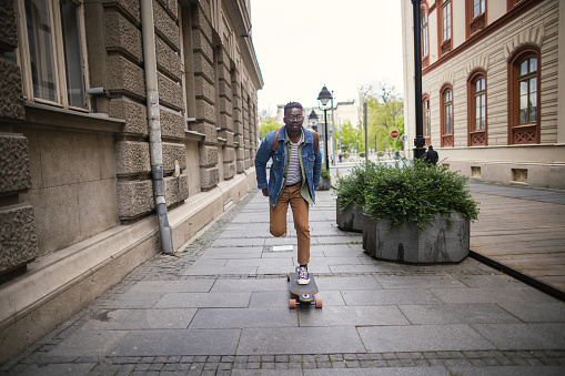 Photo of Young handsome man driving skateboard on the city street