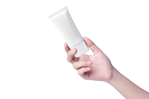 Woman hand hold white plastic cream tube isolated on white background.