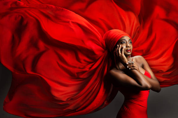 붉은 실크 머리 스카프에있는 아프리카 흑인 여성. 패션 다크 스킨 모델 초상화 터번에서 골든 쥬얼리와 함께 회색 배경 위에 시폰 패브릭을 날리고 있습니다. 세련된 아랍 뷰티 여성 모자 - veil human face women fashion model 뉴스 사진 이미지