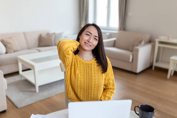 istock Feeling exhausted. Frustrated Asian woman looking exhausted and massaging her neck while sitting at her working place 1393072050