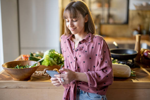 istock Woman using smatphone while cooking healthy at home 1393074547
