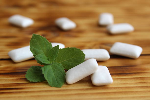 Chewing gum pads with mint lie on a wooden table.