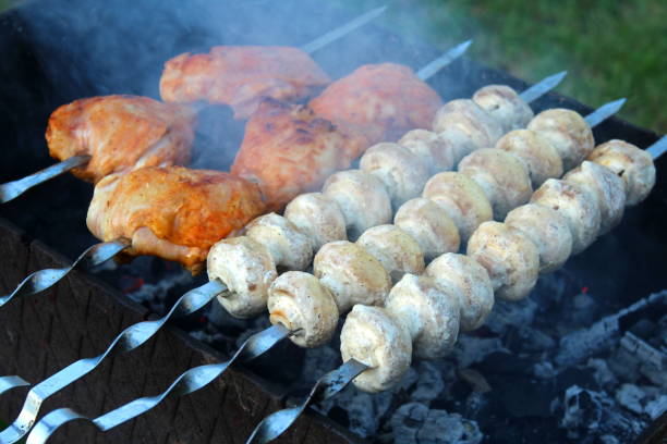 les champignons et la viande de poulet sont frits sur le gril. - rotisserie chicken barbecue grill food photos et images de collection