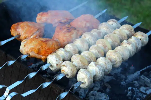 Mushrooms and chicken meat are fried on the grill.