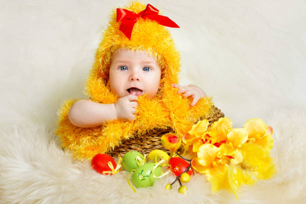 пасхальный младенец. новорожденный ребенок в курином костюме вылупляется. младенец в желтой пушистой шляпе сидит внутри корзины с пасхаль� - baby chicken eggs young bird easter стоковые фото и изображения
