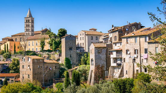 An idyllic skyline of the medieval heart of Viterbo, in central Italy, with the bell tower of the Cathedral of San Lorenzo (Saint Lawrence) and a glimpse of the village of San Pellegrino. The historic center of Viterbo, the largest in Europe with countless historic buildings, churches and villages, stands on the route of the ancient Via Francigena (French Route) which in medieval times connected the regions of France to Rome, up to the commercial ports of Puglia, in southern Italy, to reach the Holy Land through the Mediterranean. Located about 100 kilometers north of Rome, in the Lazio region, Viterbo is also known as the City of Popes because in the 13th century it was the seat of papal power for 24 years. Founded by the Etruscan civilization and recognized as a city in the year 852, Viterbo is characterized by its peperino stone and tuff constructions, materials abundantly present in this region of central Italy. Image in 16:9 and high definition format.