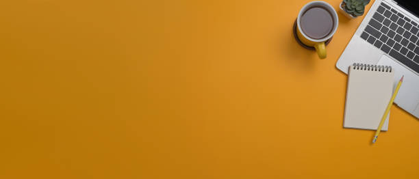 istock Laptop computer, coffee cup and notepad on yellow background with copy space for your information content. 1393088355