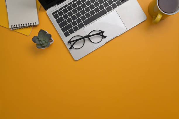 istock Stylish workplace with computer laptop, notepad, glasses and coffee cup on yellow background. Top view, Flay lay, Copy space. 1393088359