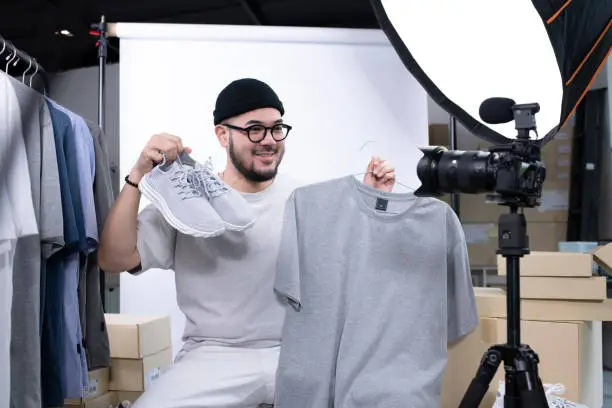 Photo of Asian man blogger or vlogger looking at camera reviewing product.