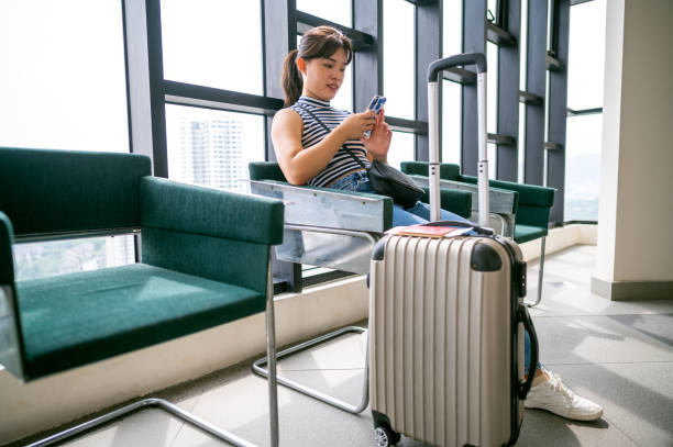 istock Woman using smartphone while waiting their transportation on a station with passport and baggage 1393092258