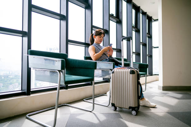 istock Woman using smartphone while waiting their transportation on a station with passport and baggage 1393092261