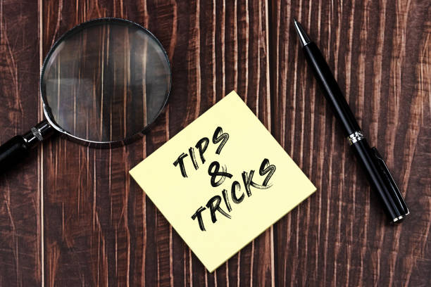Tips and Tricks text on adhesive note with magnifying glass and pen Top view of Tips and Tricks text on adhesive note with magnifying glass and pen tips tricks stock pictures, royalty-free photos & images