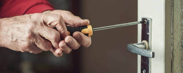 mature locksmith with screwdriver in hands repairing lock of door - holding screwdriver imagens e fotografias de stock