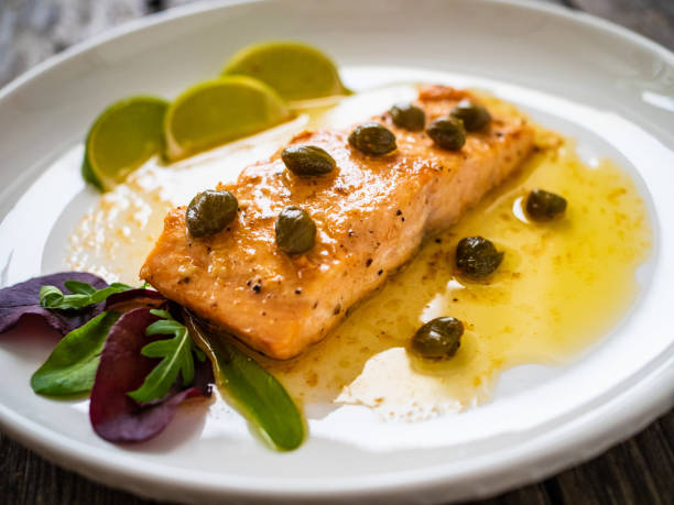 istock Butter sauce fried salmon steak with capers and lime on wooden table 1393095657