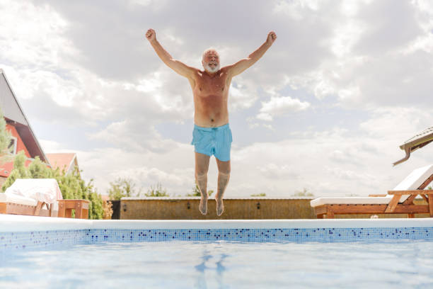 un homme âgé saute dans la piscine - active seniors retirement enjoyment swimming pool photos et images de collection