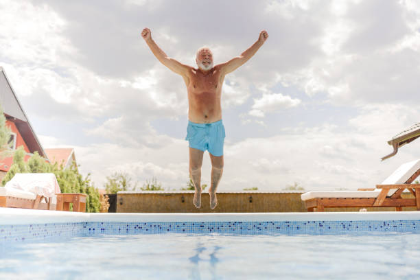 istock Senior man jumping into the swimming pool 1393097710