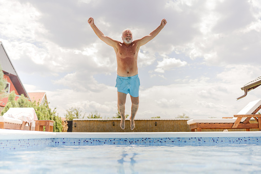 Photo of a senior man jumping into the swimming pool