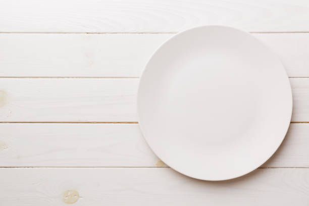 istock Top view of empty light plate on wooden background. Empty space for your design 1393098877