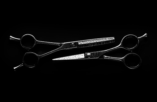 Professional Barber Scissors with water drops on black background.