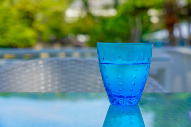 Front closeup view of a glass full of water and bubbles. The glass is at the right side of the image leaving a useful copy space at the left side on a gradient blue background.