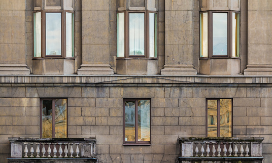 Two balconies and several windows in a row on the facade of the urban historic apartment building front view, Saint Petersburg, Russia