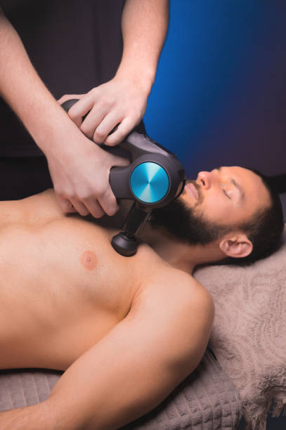 istock A professional masseur makes a relaxing massage to a male client with a percussion massager 1393104160