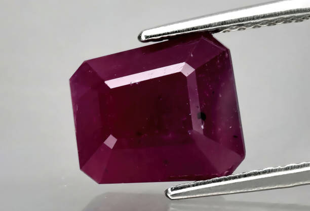 istock Natural gemstone red ruby in tweezers on a gray background 1393108621