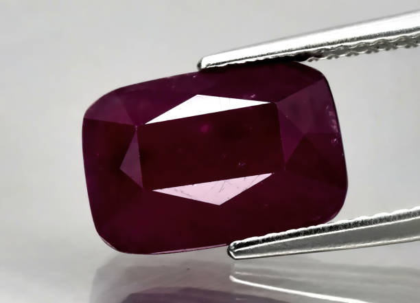 istock Natural gemstone red ruby in tweezers on a gray background 1393108634