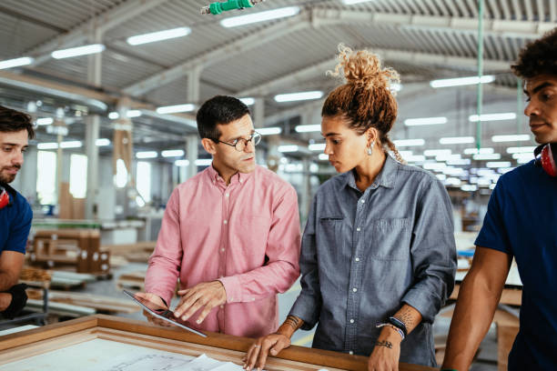 Architects, engineers and blue collar staff working together in modern factory stock photo