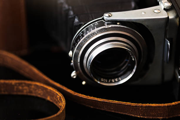Antique folding bellows camera with leather strap Close-up of lens and shutter and aperture dials of an antique camera from the 1950s. bellows stock pictures, royalty-free photos & images