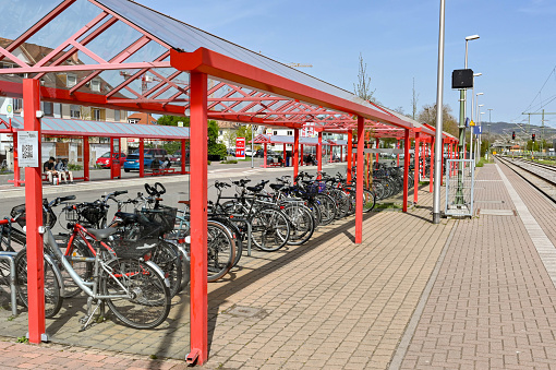 Breisach, Germany - April 2022: Canopy covering the large bicycle parking area on the platform at Breisach railway station. In the background is the bus stop, where bus times are matched to train arrival and departure times