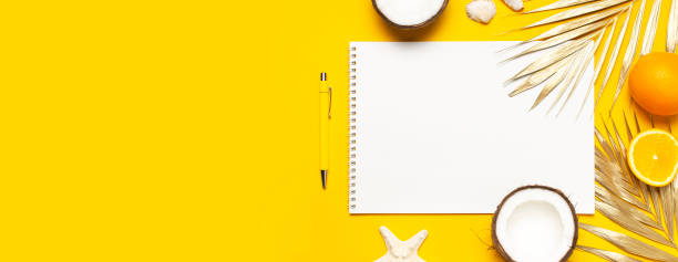 istock Flat lay Summer background. Open notebook with clean white pages on a spiral, golden tropical leaves, coconut, orange, shells starfish on yellow background top view. Summer Beach template for design 1393120702