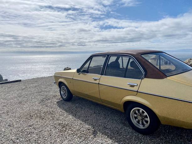 Classic car parked on cornish cliff overlooking sea