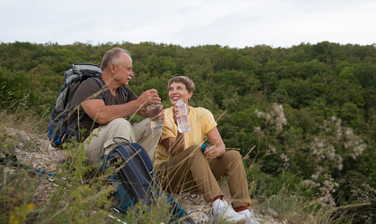 Senior tourist couple sitting on the mountain. Senior couple walking in nature.  travel tourism concept. Outdoor activities on weekends.