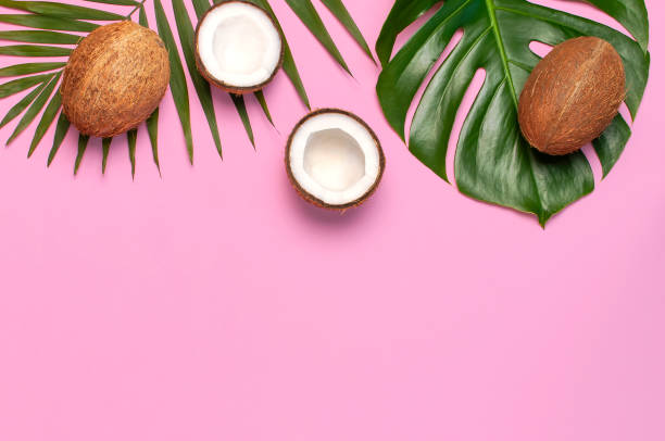istock Tropical leaves and fresh coconut on pink background. Flat lay, top view, copy space. Summer background, nature. Healthy cooking. Creative healthy food concept, half of coconut 1393124864