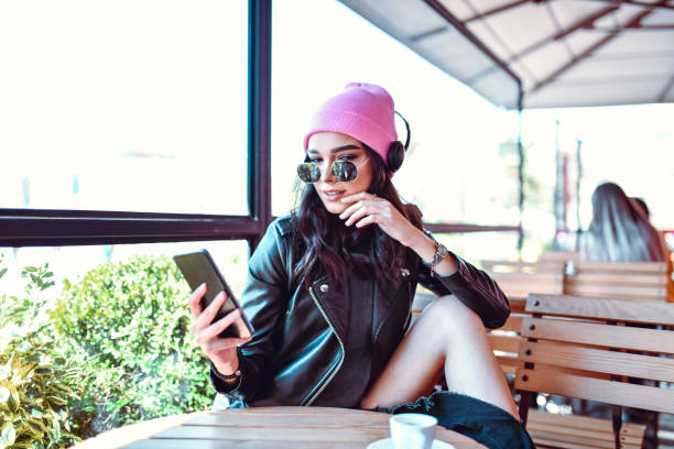 istock Beautiful Female Enjoying Music On Smartphone While Drinking Coffee 1393125796