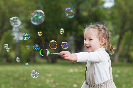 happy and healthy childhood. A little girl blows bubbles in a summer park.
