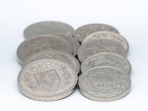 two lying stacks of coins, 5 franc coins on the left and 2 franc coins on the right. focus on the front coins. The Swiss Franc is the currency of the Swiss Confederation and the Principality of Liechtenstein. The swiss franc (CHF) is issued by the swiss national bank (SnB).