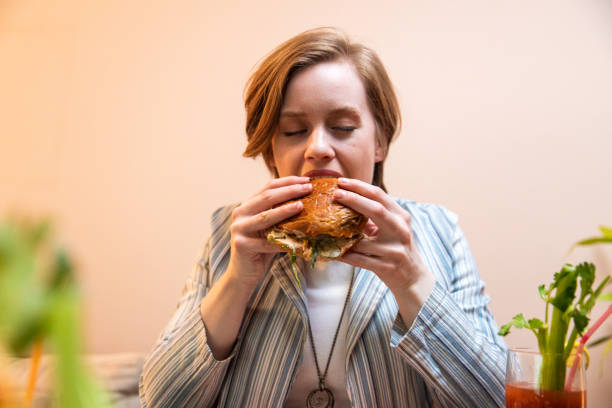 istock Young woman enjoying eating burger and drinking cocktail 1393130584