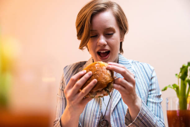 istock Young woman enjoying eating burger and drinking cocktail 1393130620
